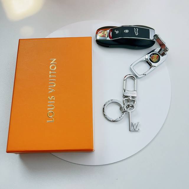 Lv Key 精钢钥匙扣令经典 Lv 字母附着于钥匙挂坠，后者镂刻路易威登标识，凝聚潮流气息和经典底蕴。